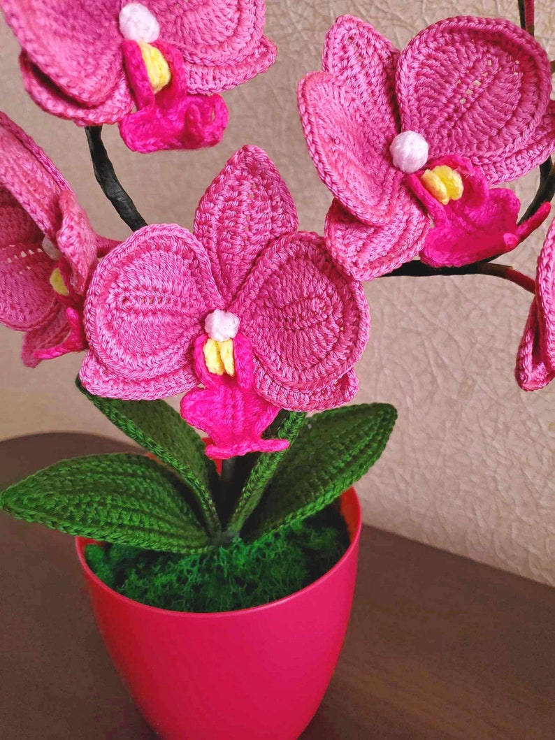 Gehaakt bloemdecor roze orchidee met gebogen stelen en groene bladeren in pot