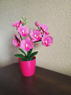 Gehaakt bloemdecor roze orchidee met gebogen stelen en groene bladeren in pot