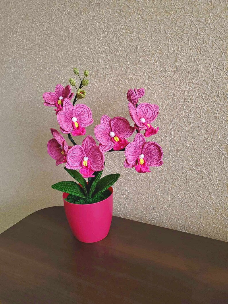 Gehaakt bloemdecor roze orchidee met gebogen stelen en groene bladeren in pot