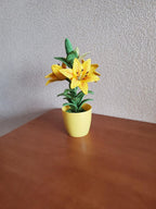 Gehaakte lelieplant in gele pot, handgemaakt botanisch decor met goudgele bloemen